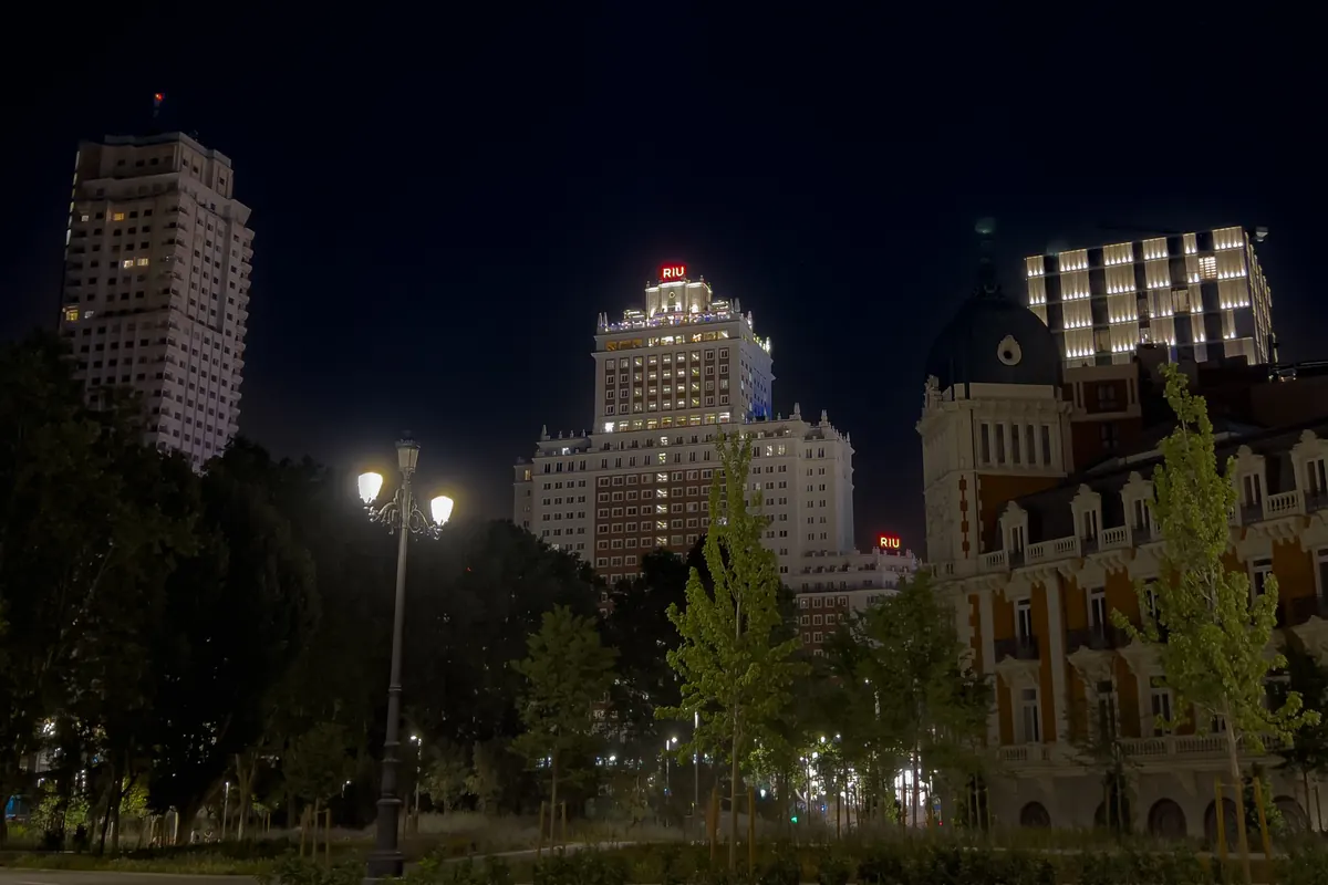 Edificios iluminados, árboles y una farola en la Plaza de España de noche.